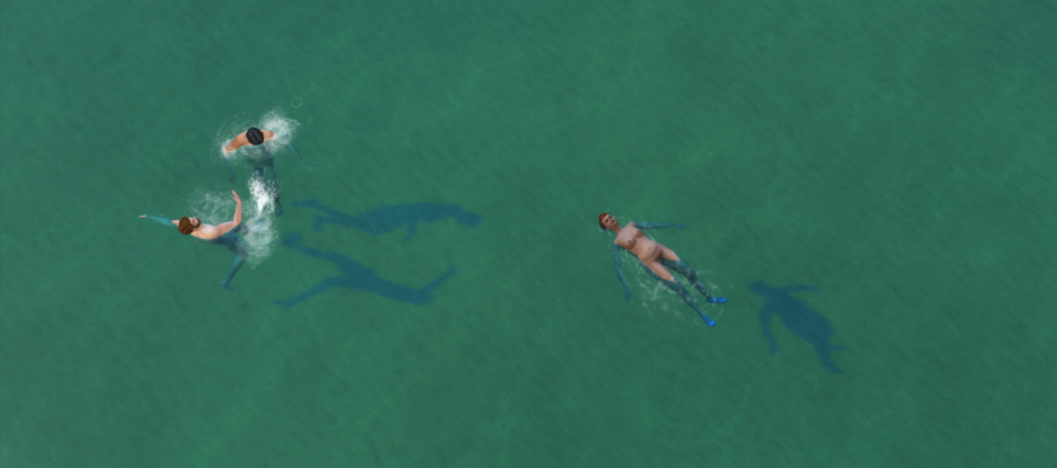 Kyle floats on their back in the ocean While Alex and Avery have a splash fight near by.